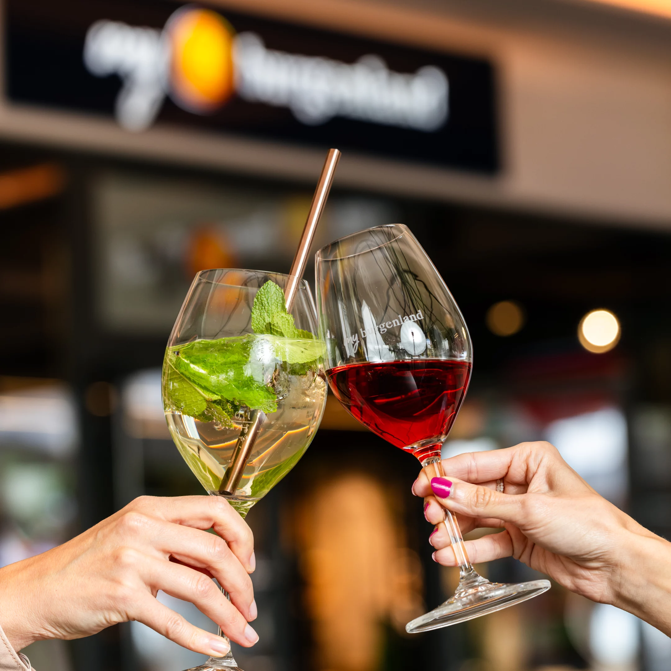 Zwei Gläser beim Anstoßen vor dem my burgenland Shop in Parndorf